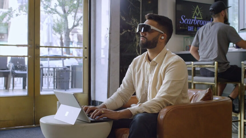 Une personne travaille sur son ordinateur portable et porte une visière immergée alors qu'elle est assise dans un café.