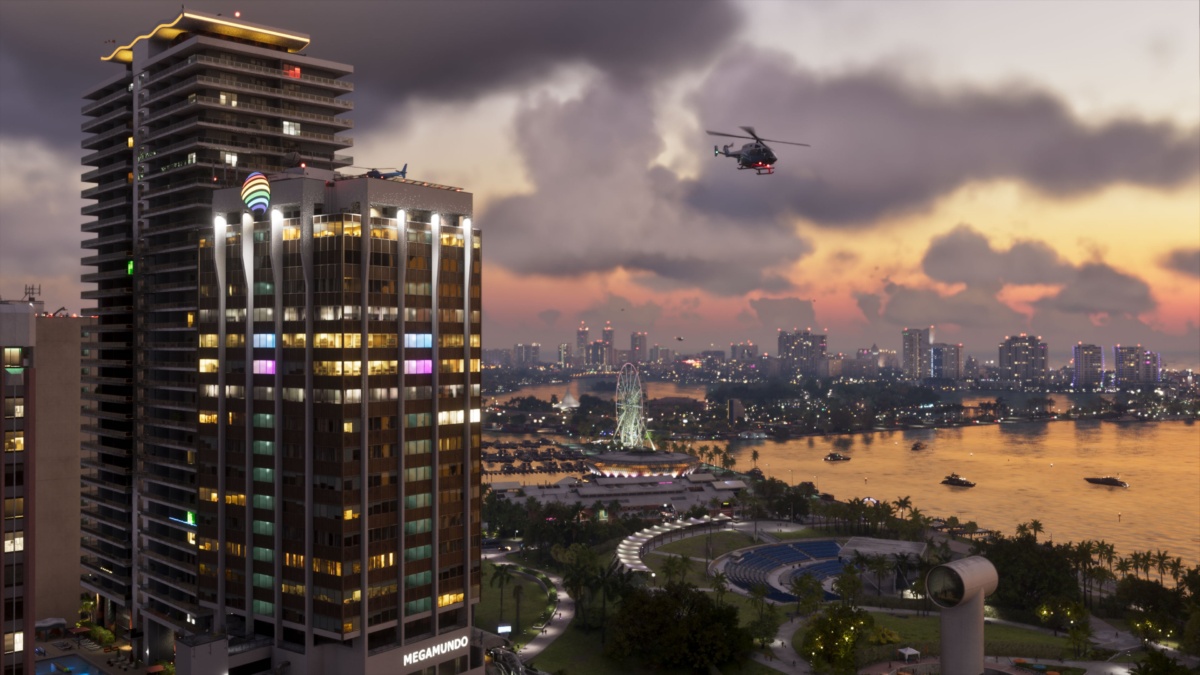 Des hélicoptères volent à côté de la tour Megamundo illuminée de Vice City au-dessus du front de mer au crépuscule dans une capture d'écran officielle de GTA VI.